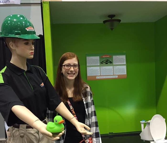 A woman is standing next to a mannequin dressed as a SERVPRO employee