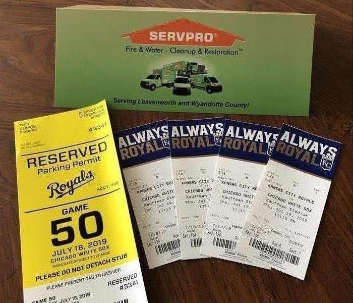 A SERVPRO table topper sign with a set of four Royals tickets and a parking pass in front of it