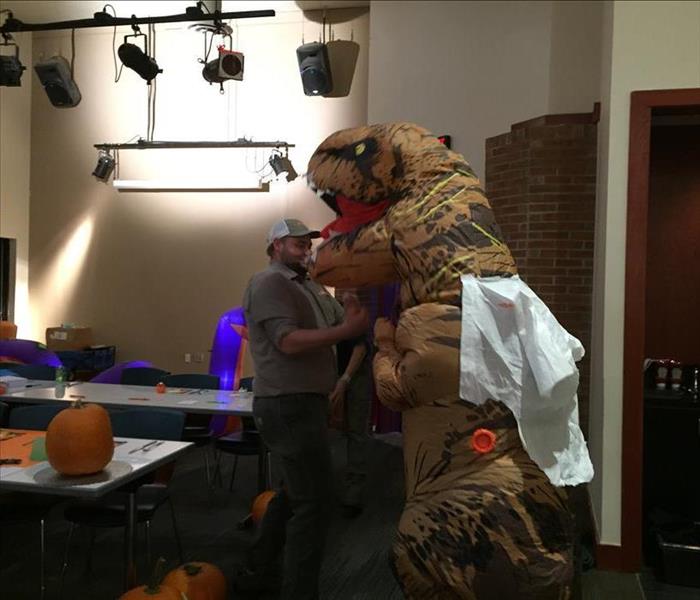 A SERVPRO employee in a blow up TRex costume is pretending to fight another SERVPRO employee
