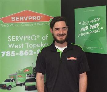 A male SERVPRO employee is standing in front of a SERVPRO sign.
